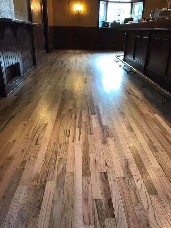 Empty room with polished wooden floor, dark walls, and bright light from a window at the far end