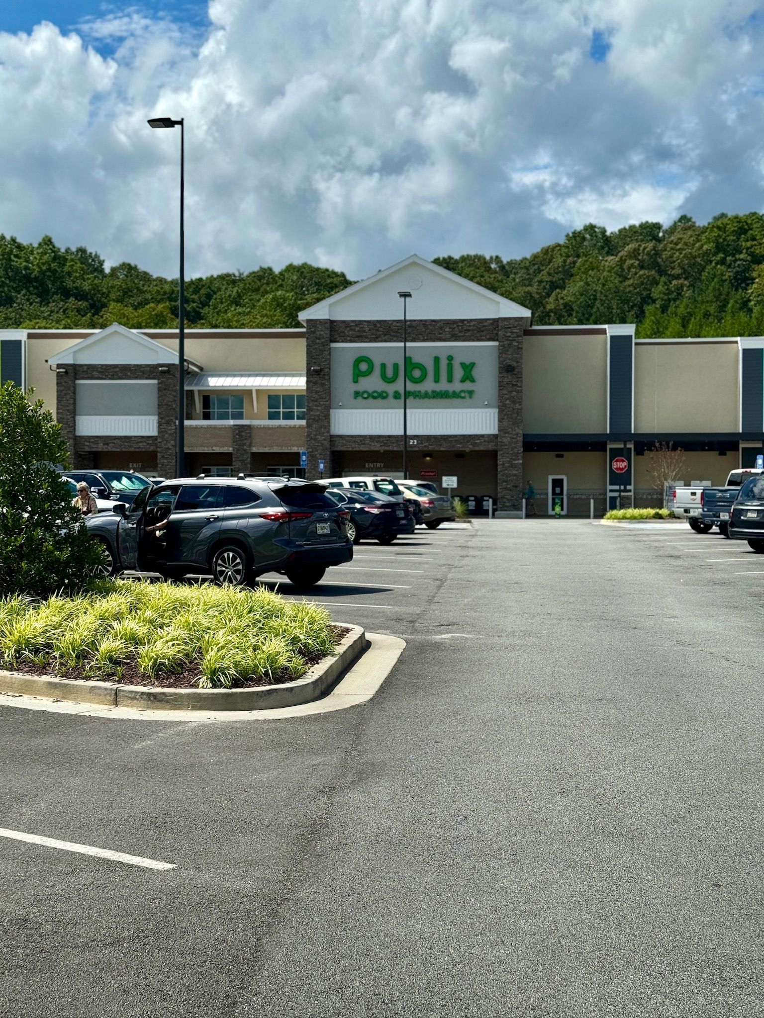 Publix grocery store exterior with cars parked in front. Cloudy sky.