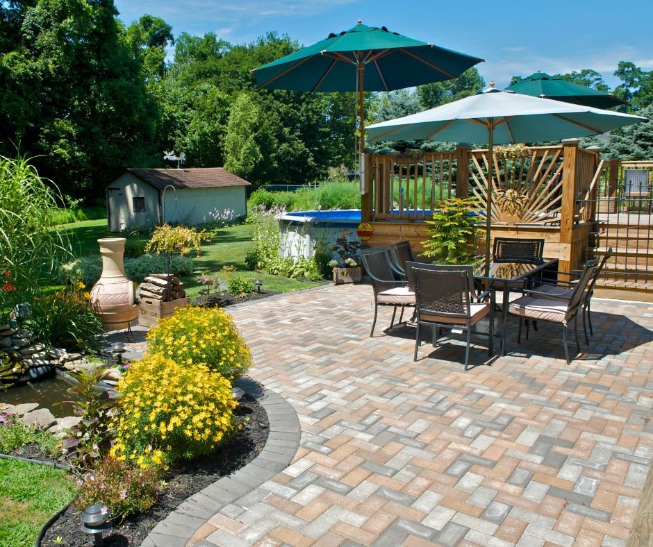 Brick patio with dining set under an umbrella. Includes a small above-ground pool and landscaping in a backyard setting.