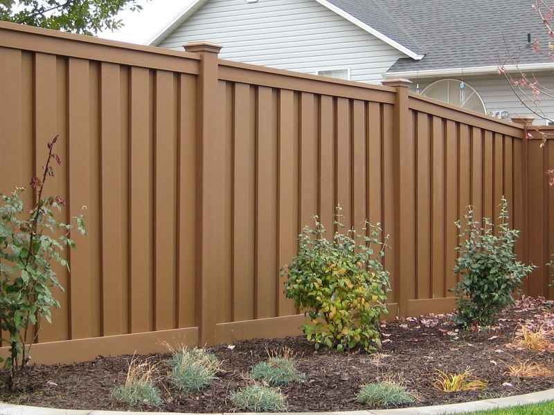 Trex fence in a yard with landscaping and a house in the background.