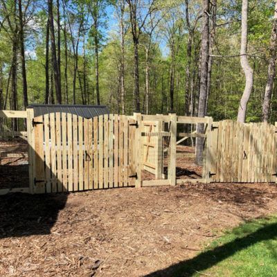 A wooden fence with a gate in the middle of a forest.