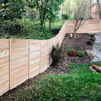 A wooden fence is surrounding a lush green yard.