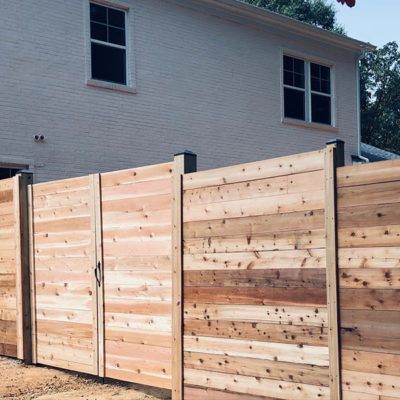 A wooden fence is in front of a white house.
