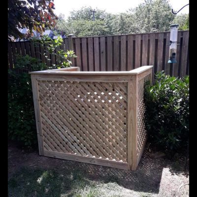 A wooden box is sitting in the grass next to a wooden fence.