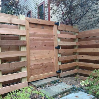 A wooden fence with a gate in front of a house.