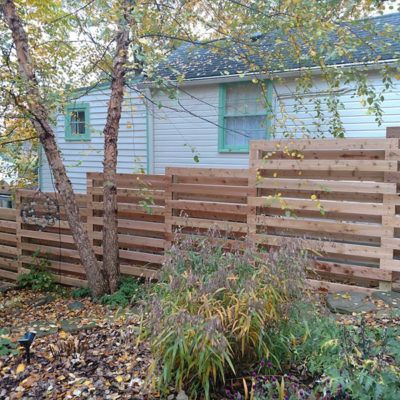 A wooden fence is in front of a white house.