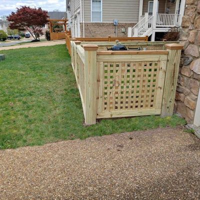 A wooden fence with a lattice gate is in the backyard of a house.