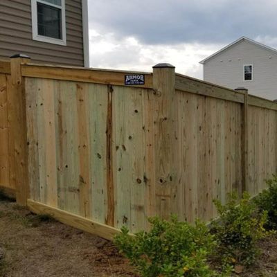 A wooden fence is sitting in front of a house.