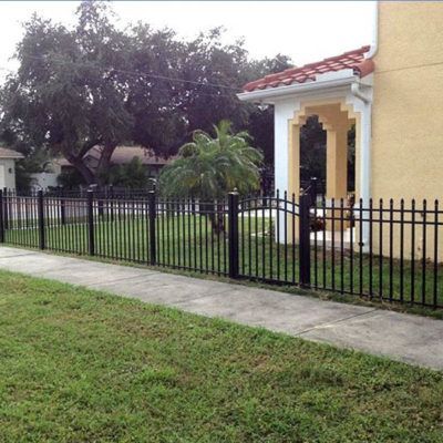 A yellow house with a black fence in front of it