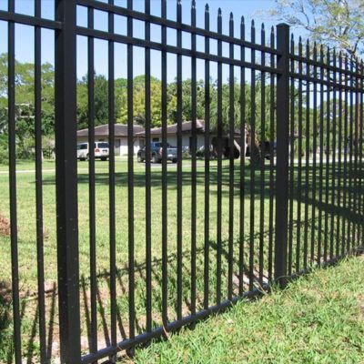A black wrought iron fence surrounds a lush green field.