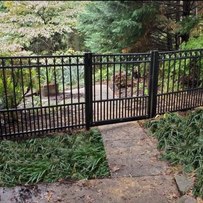 A black wrought iron fence with a gate leading to a path.