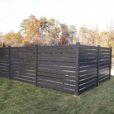 A black wooden fence is sitting in the middle of a lush green field.