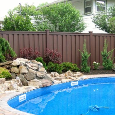 A swimming pool with a brown fence and a waterfall