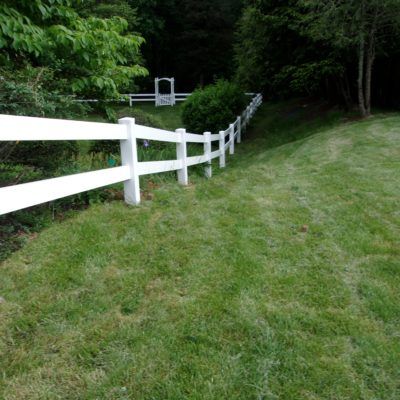 A white fence surrounds a lush green field.