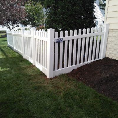 A white picket fence is sitting in the grass next to a house.