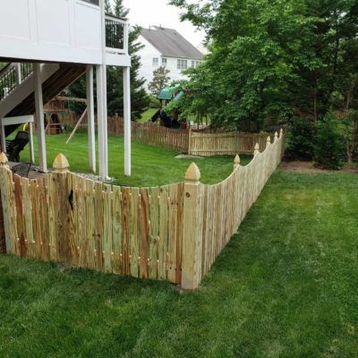 A wooden fence surrounds a lush green yard