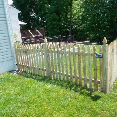 A wooden picket fence surrounds a lush green yard