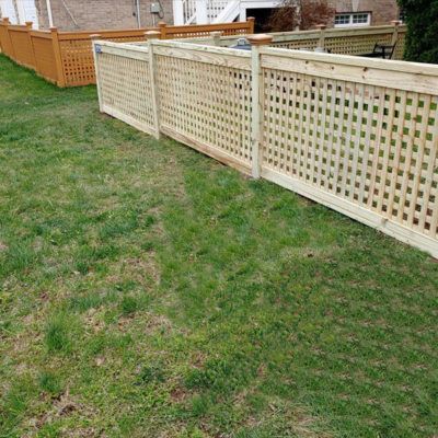A wooden fence is sitting in the middle of a lush green yard.