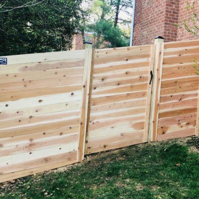 A wooden fence with a gate in the backyard of a house.