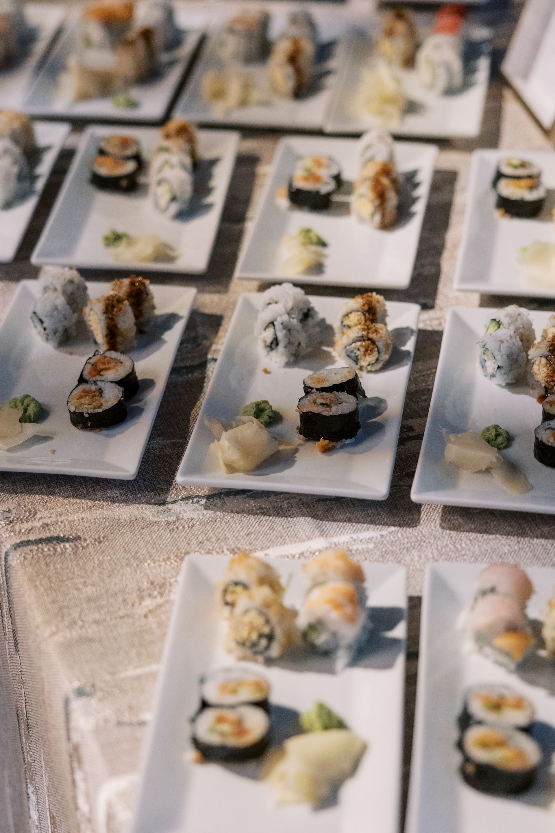 Plates of sushi rolls and nigiri are arranged on a table, ready to be served.
