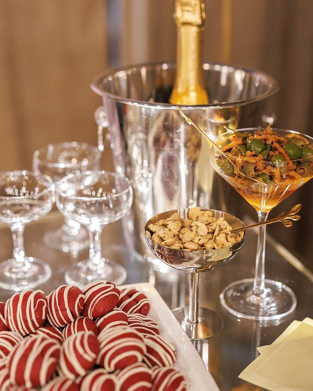 Champagne, martini, snacks, and treats on a mirrored tray; celebratory setting.