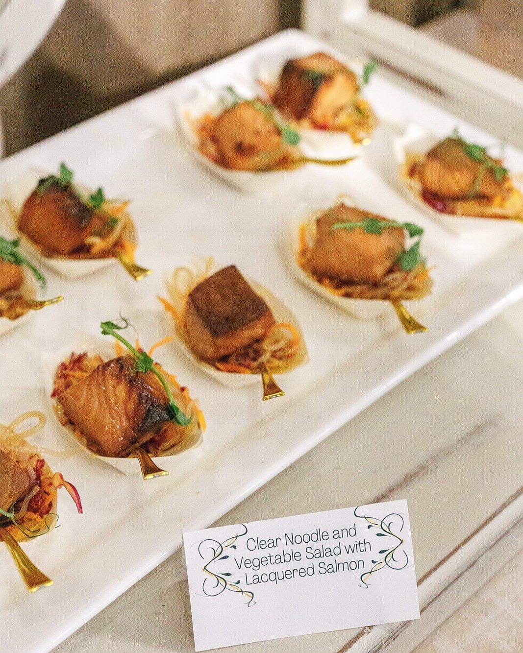 Small appetizer bites on white tray: fried food on small, leaf-shaped containers with greens.