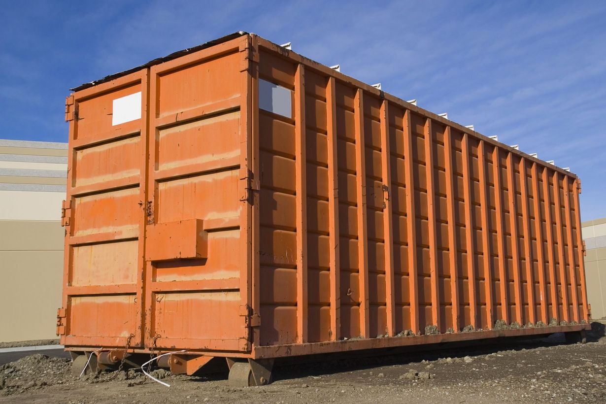 Orange rectangular metal container outdoors against a blue sky.