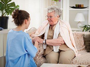Nurse in home visit holding hands with old patient
