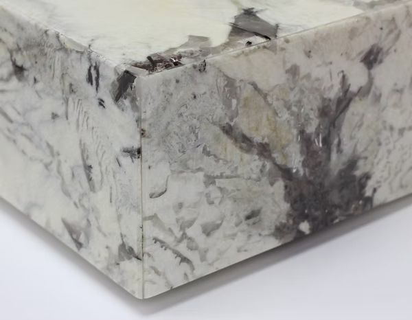 Close-up of a white and gray countertop corner. The surface has dark speckles and veining.