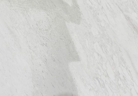 Textured light gray surface with subtle shading and streaks.