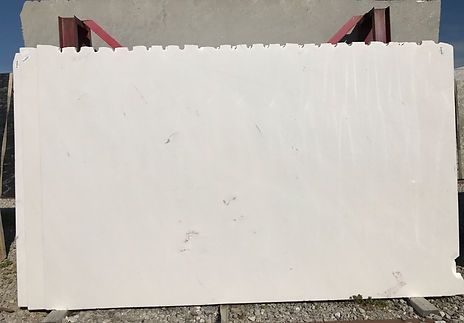 Large rectangular white stone slab with jagged top edge, outdoors.