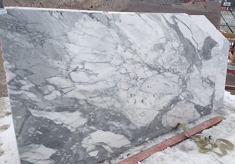 Large marble slab with gray and white veining, set outside in snow.