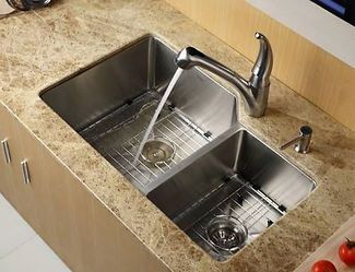 Stainless steel double sink with water running, on a beige countertop.