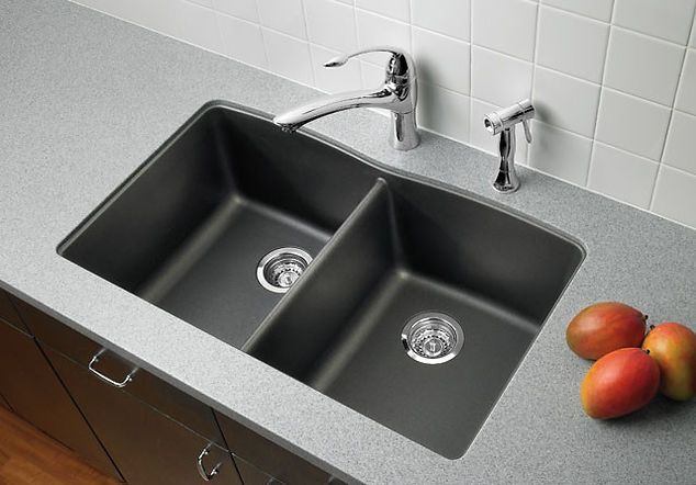 Dark double kitchen sink with chrome faucet, countertop, and mangoes.