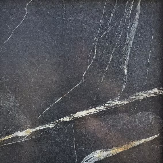 Dark gray stone tile with white and gold veining.