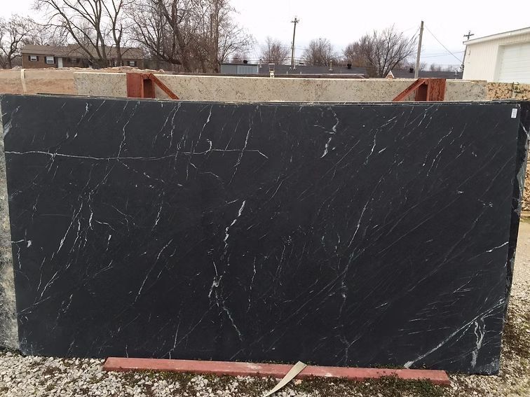Black marble slab with white veining, displayed outdoors on supports.