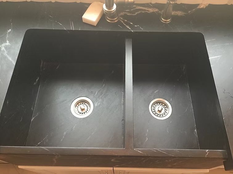 Black double kitchen sink with a light marble-like pattern, installed in a countertop.