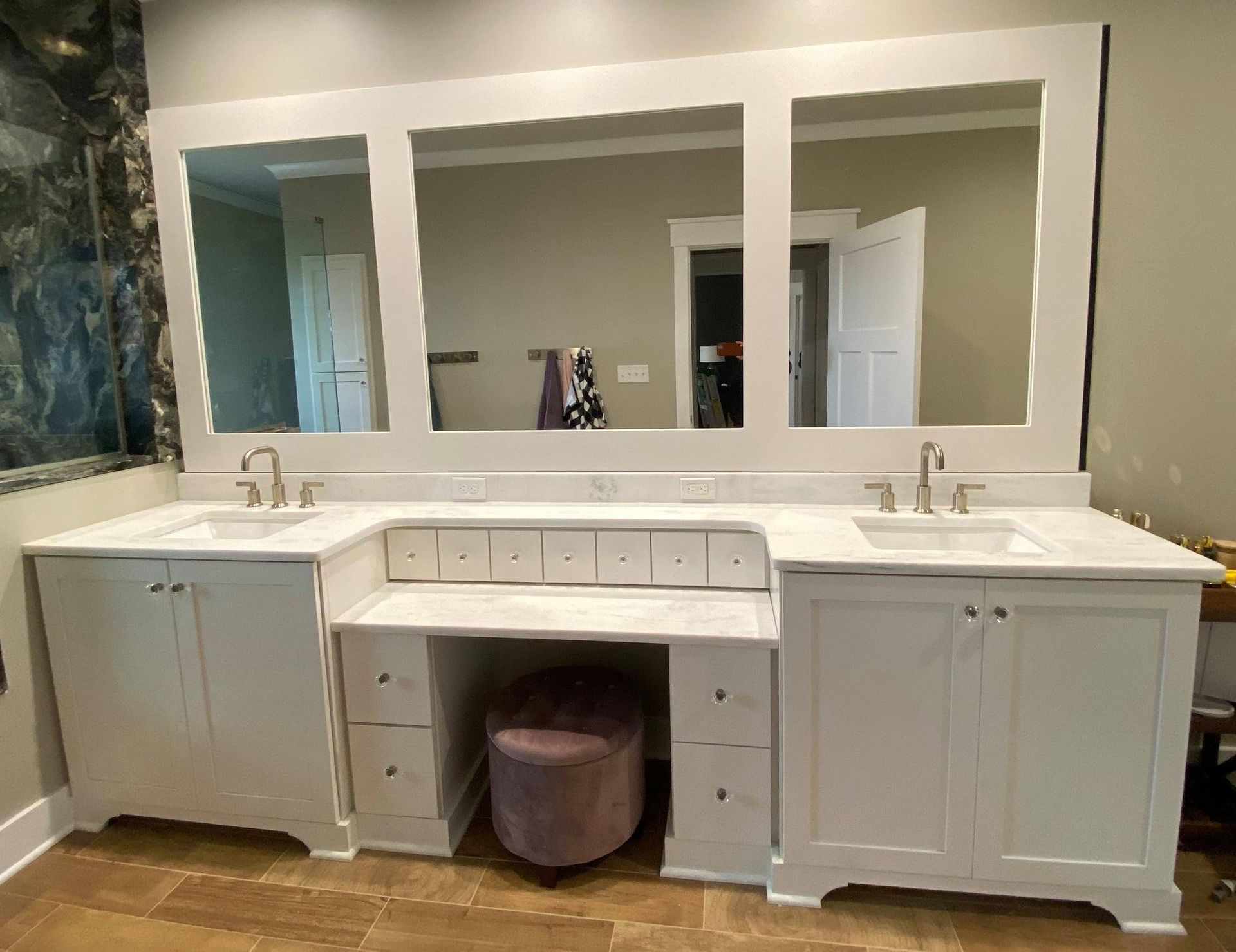 White bathroom vanity with three mirrors, two sinks, and a makeup area.