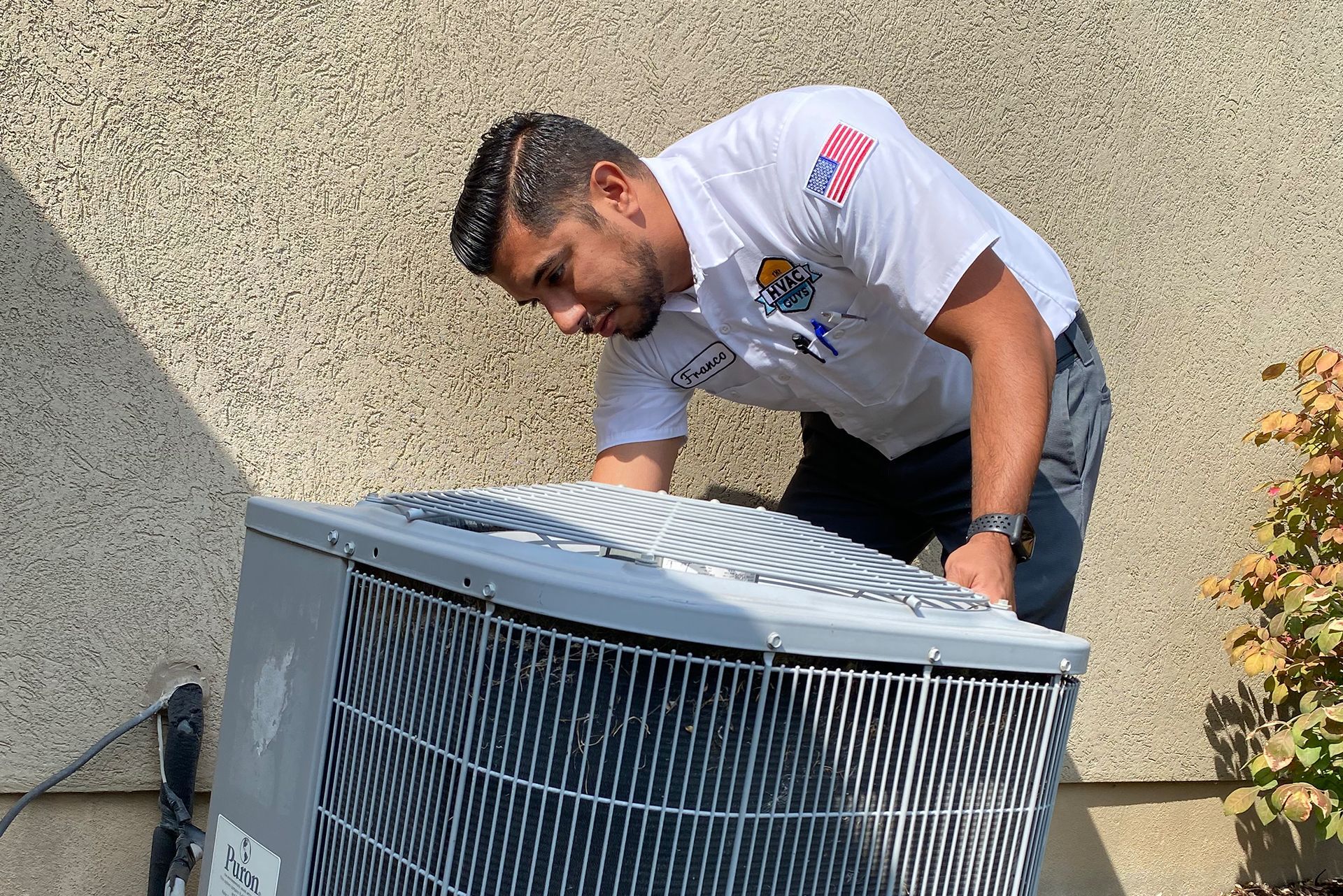 HVAC technician inspects an air conditioning unit outdoors.