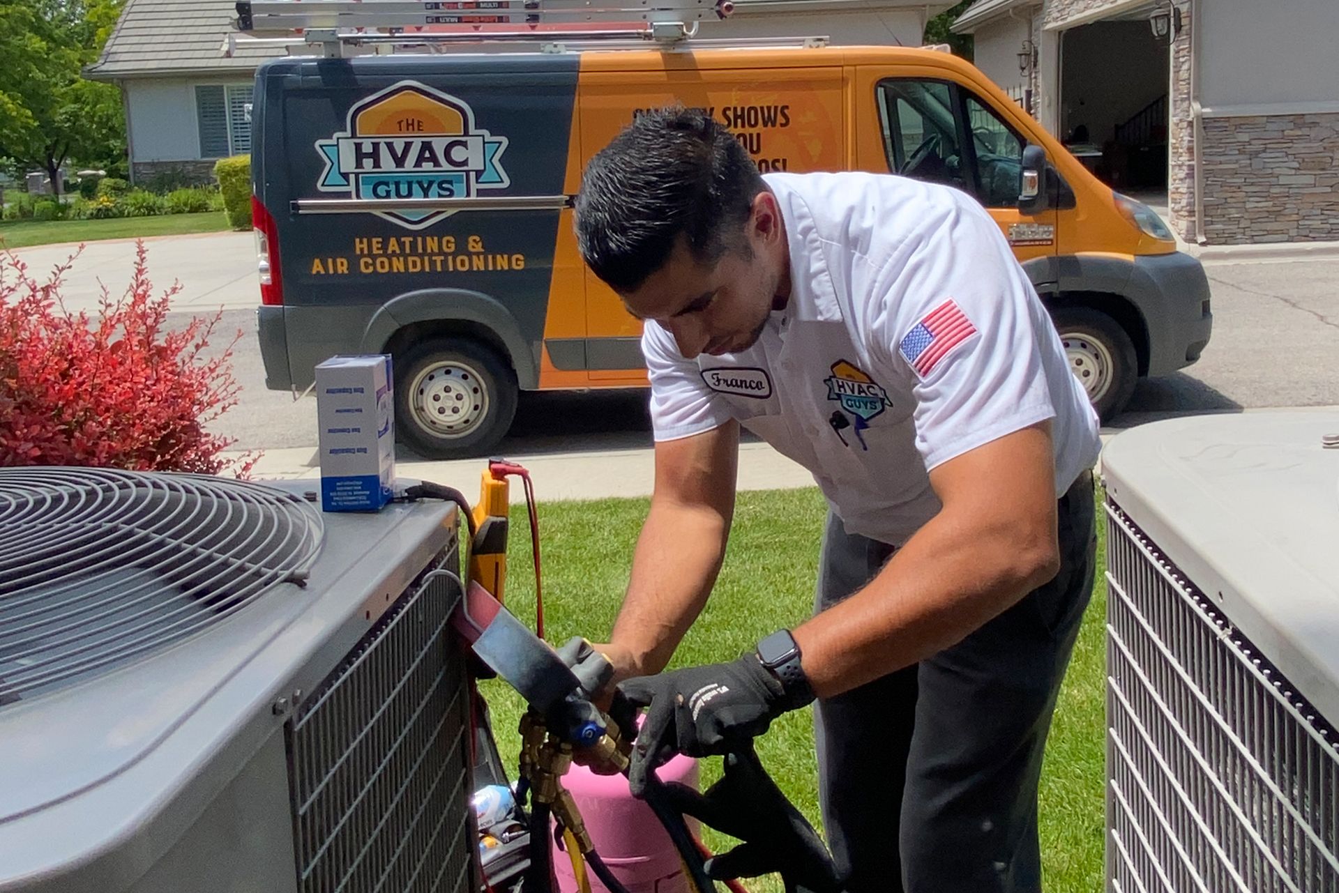 HVAC technician working on an air conditioning unit outside, near a company van. He's using tools, with grass and a house in the background.