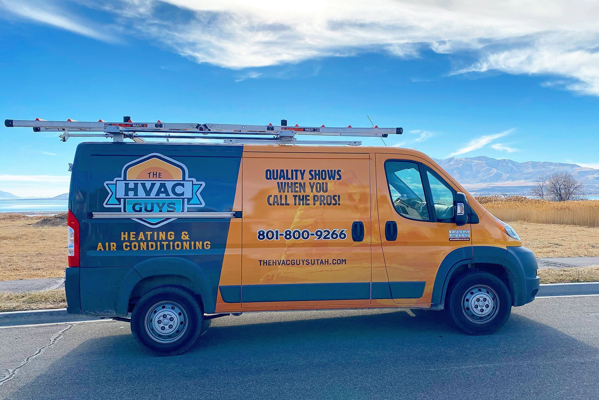 Yellow and gray HVAC service van with ladder on roof; mountains and blue sky in background.