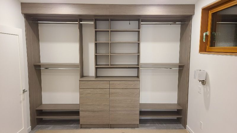 A walk in closet with lots of shelves and drawers and a window.