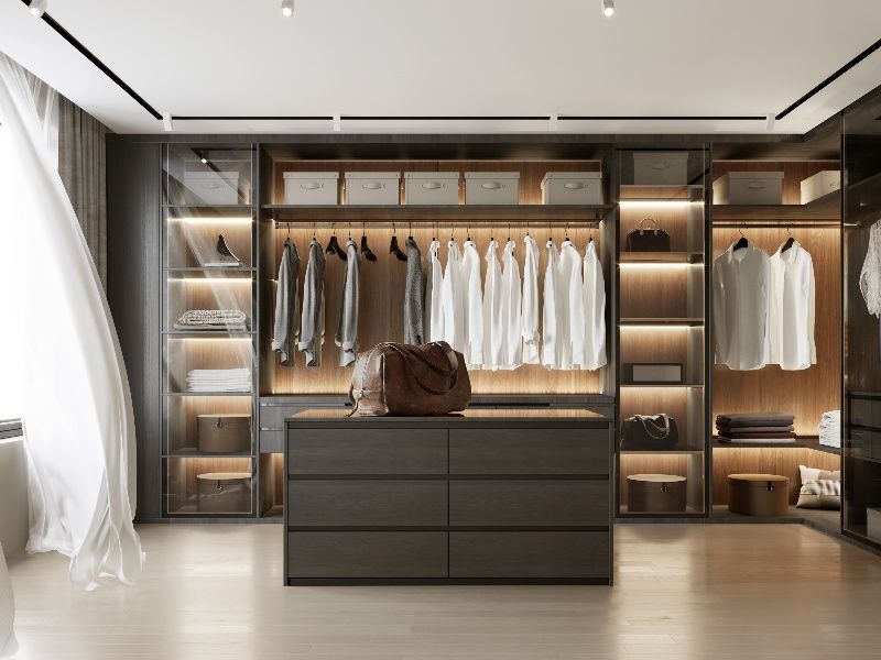 A walk in closet filled with clothes and a dresser.