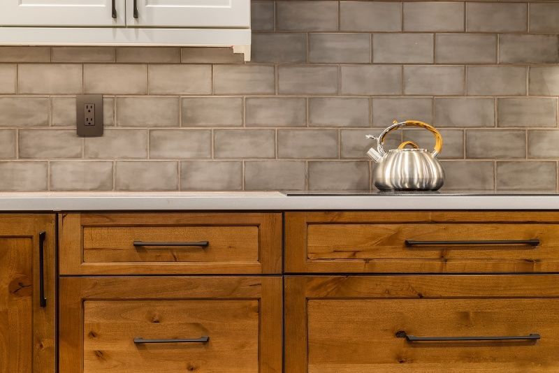 A kitchen with wooden cabinets and a tea kettle on the counter.