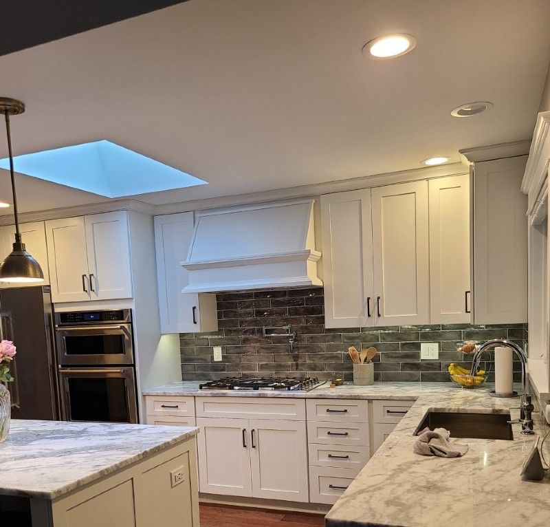 A kitchen with white cabinets and marble counter tops