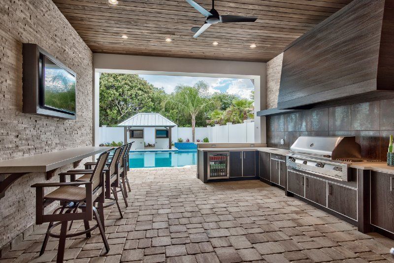A large outdoor kitchen with a grill and a television.