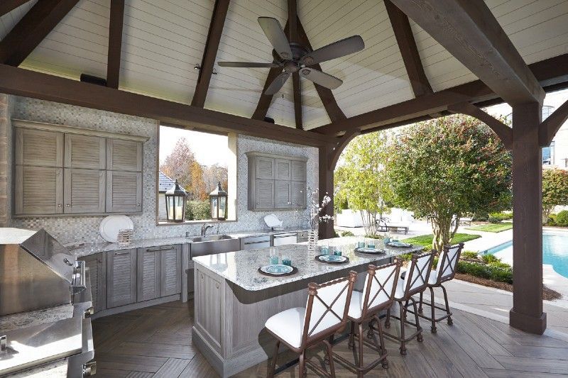 A kitchen with a table and chairs under a gazebo with a ceiling fan.