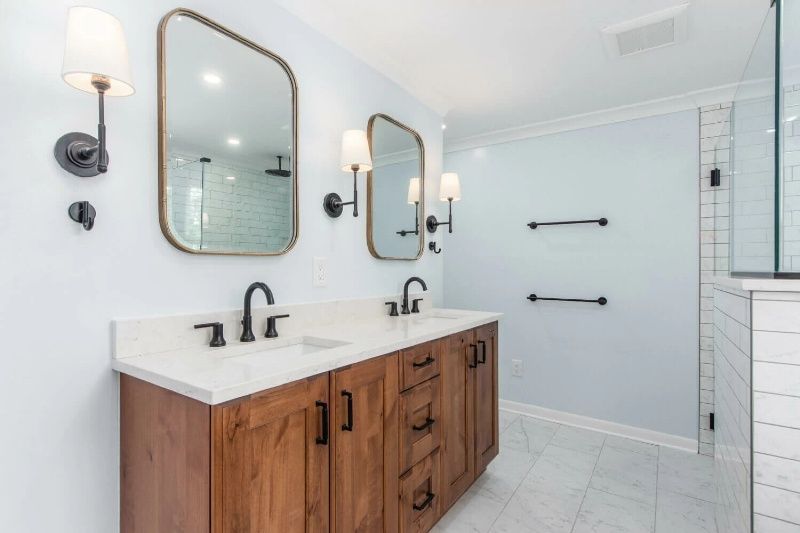 A bathroom with two sinks , two mirrors , and a walk in shower.