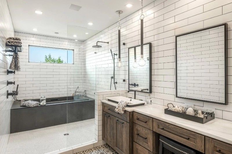 A bathroom with white tiles , a walk in shower , a sink , and two mirrors.