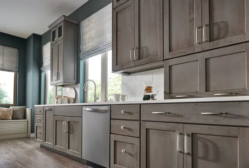 A kitchen with gray cabinets and a stainless steel dishwasher.